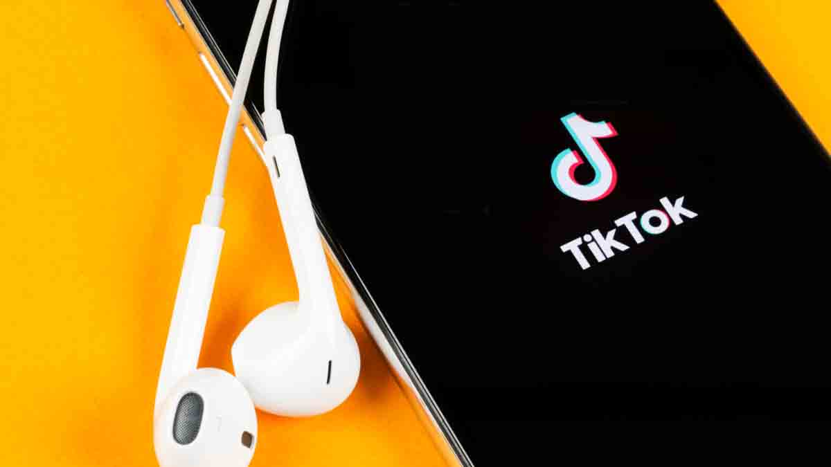 Smartphone with TikTok app open and earphones beside it, illustrating TikTok for eCommerce marketing in 2025.